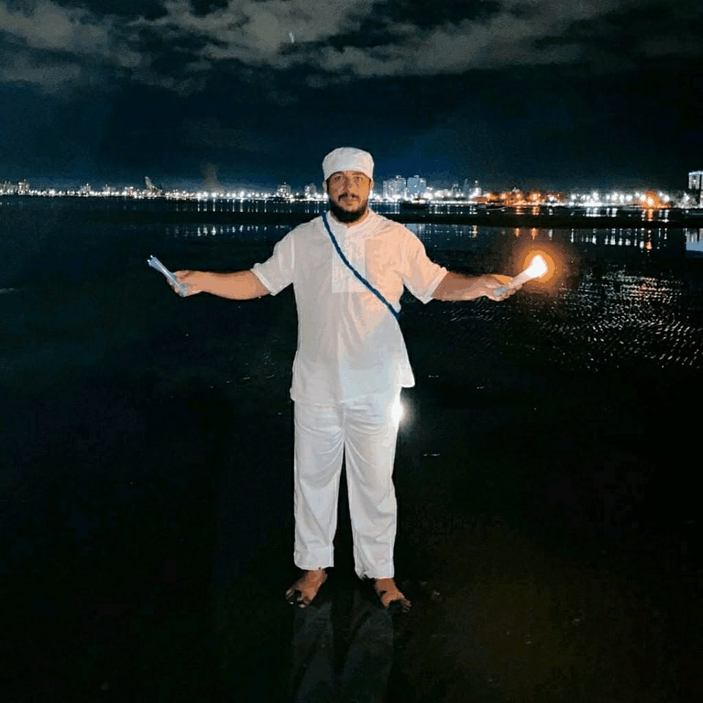 Mestre Rubens de branco em ritual de proteção na praia à noite