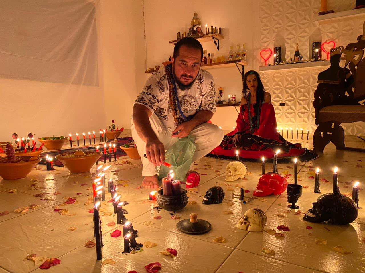 Mestre Rubens conduzindo trabalho espiritual em altar com velas e oferendas